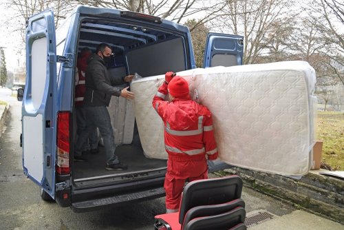 Red cross volunteer carrying mattress