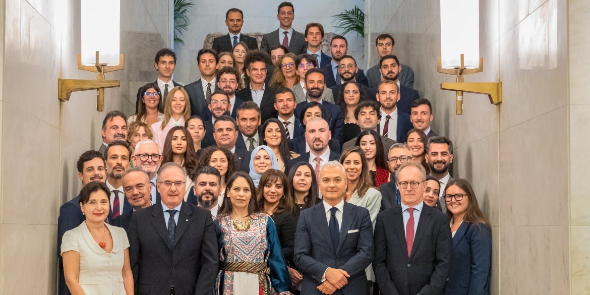 Group of delegates and officials pose for a formal group photograph on a staircase