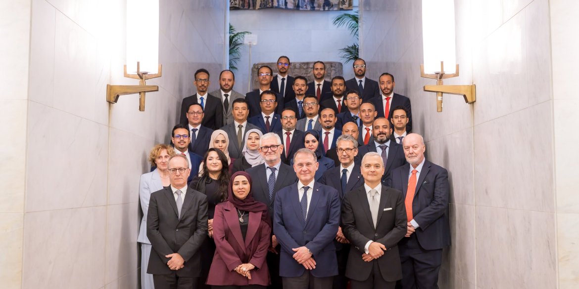 Group of delegates and officials pose for a formal group photograph on a staircase