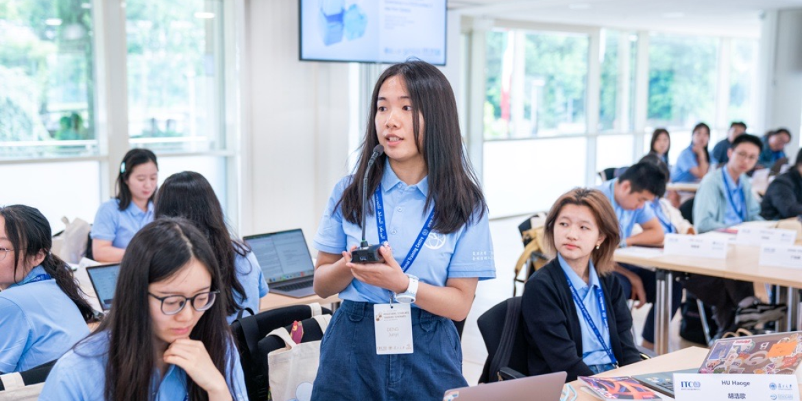 Chinese student dressed in a blue uniform speaking in a classroom