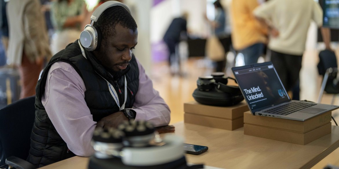 A participant wearing neurotech headphones sits at a table during the ITCILO AI+ event