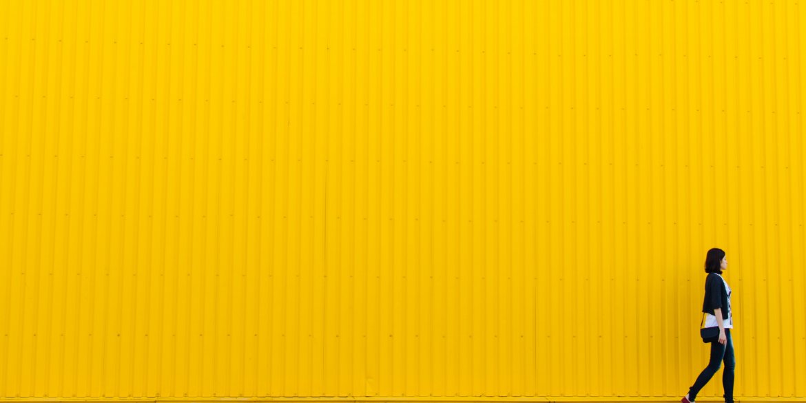 Woman walking by yellow wall