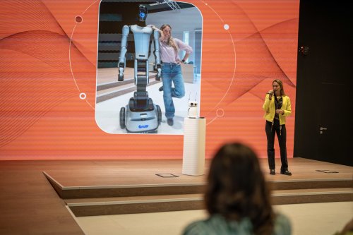 Maria Vittoria Franceschelli, ITCILO Programme Officer, speaks about physical AI and robotics alongside a  humanoid robot during Innovation Day 2026, against a red presentation screen.