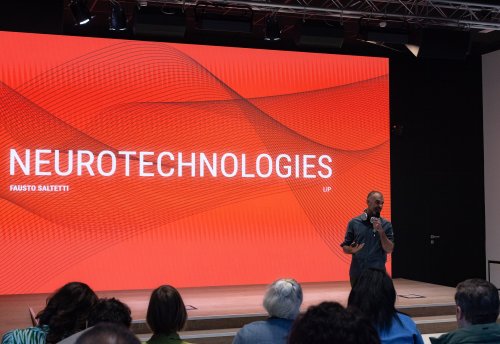 Fausto Saltetti, ITCILO Neurotechnology Lead, delivers a presentation on neurotechnologies during Innovation Day 2026, standing before a large red screen as audience members watch.