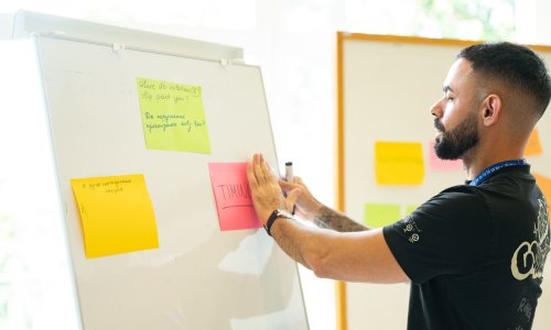 participant fixing a sticky note on a white board 