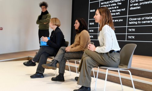 Participants take part in a presentation exercise in front of a large screen displaying a video script.