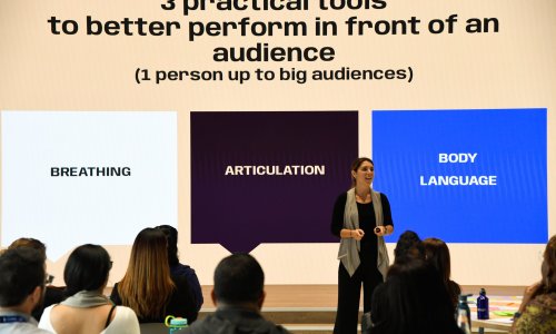A facilitator presents three practical public-speaking tools—breathing, articulation and body language—to an audience.