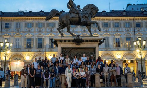 Participants of the ITCILO AI+ Nonference pose for a group photo beneath the illuminated equestrian statue in Piazza San Carlo, Turin, during an evening visit to the city.