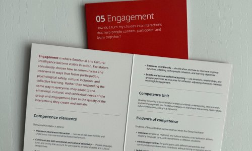 Open SENSIT toolkit booklet displaying the Empathy competency framework, with a red Empathy card positioned behind it.