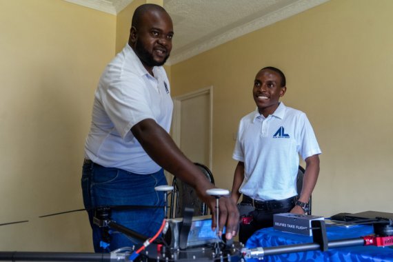 Two men standing around their drones