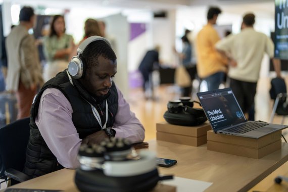 A participant wearing neurotech headphones sits at a table during the ITCILO AI+ event