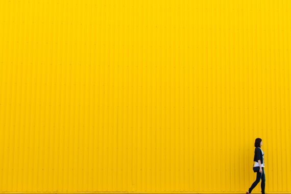 Woman walking by yellow wall