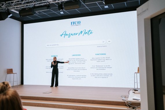 woman standing in front of large screen displaying information about ITCILO chatbot